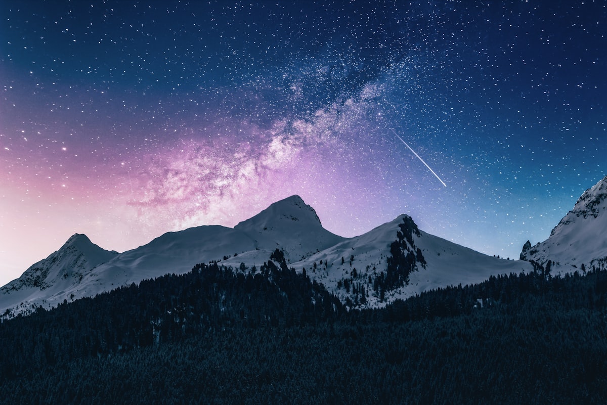 A snow-capped mountain under a starry night sky